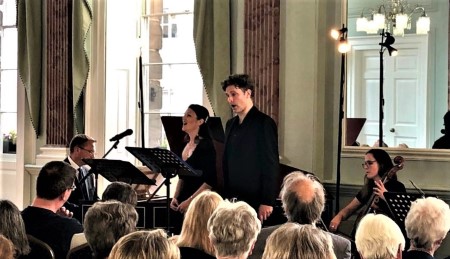 Singers and musicians perform in front of a small crowd.