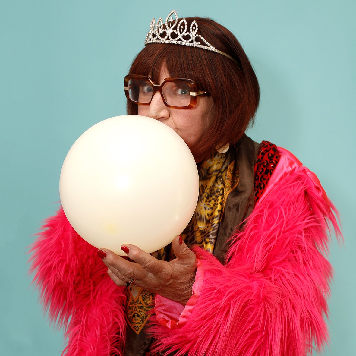 Woman in pink coat blowing up balloon